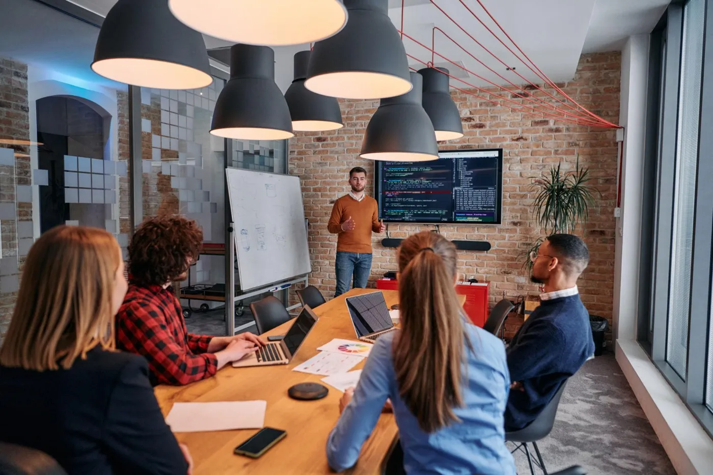 Technology team in a meeting room reviewing a presentation with code on a wall screen