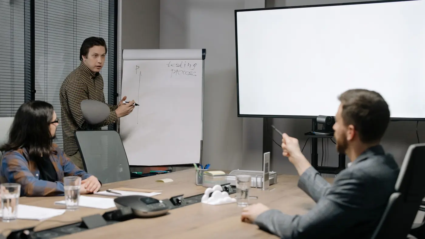 A presenter at a flip chart taking a leadership team through a sales plan in a boardroom