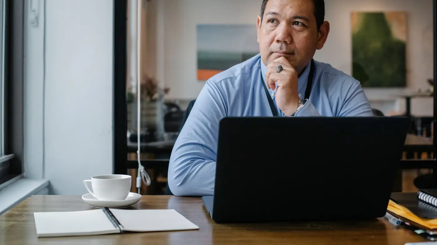 A business owner at his laptop, thinking through a decision before committing to it