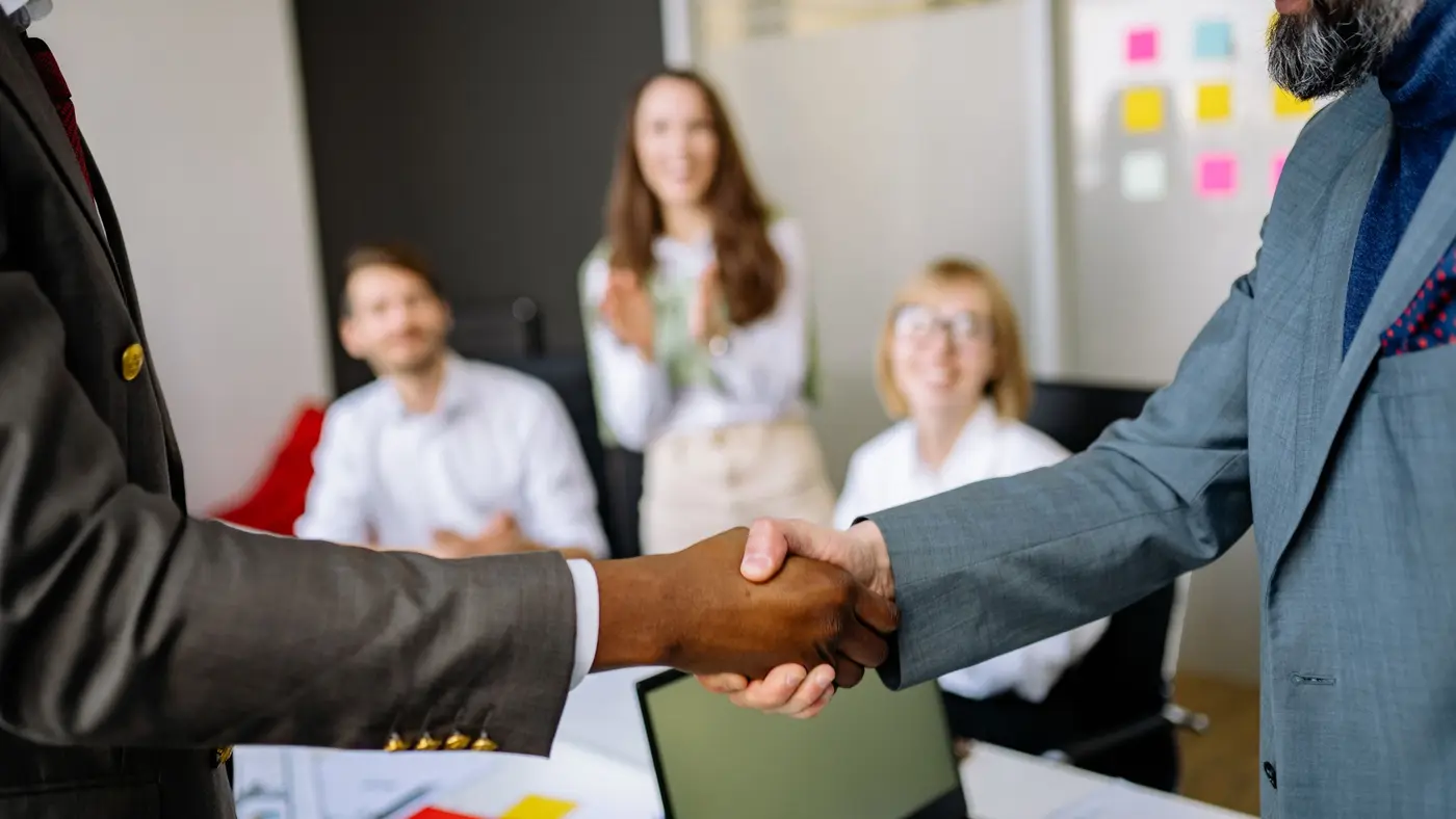 Two business people shaking hands across a meeting table