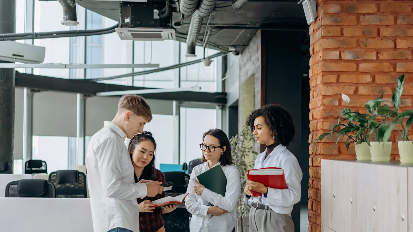 A small team standing together reviewing documents